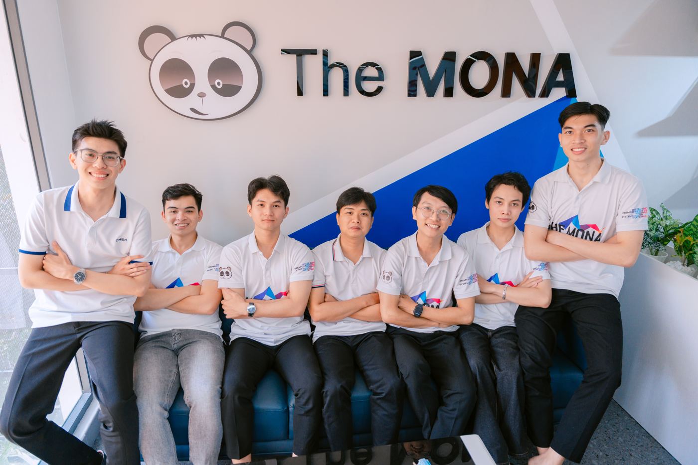Đội The MONA trước logo công ty