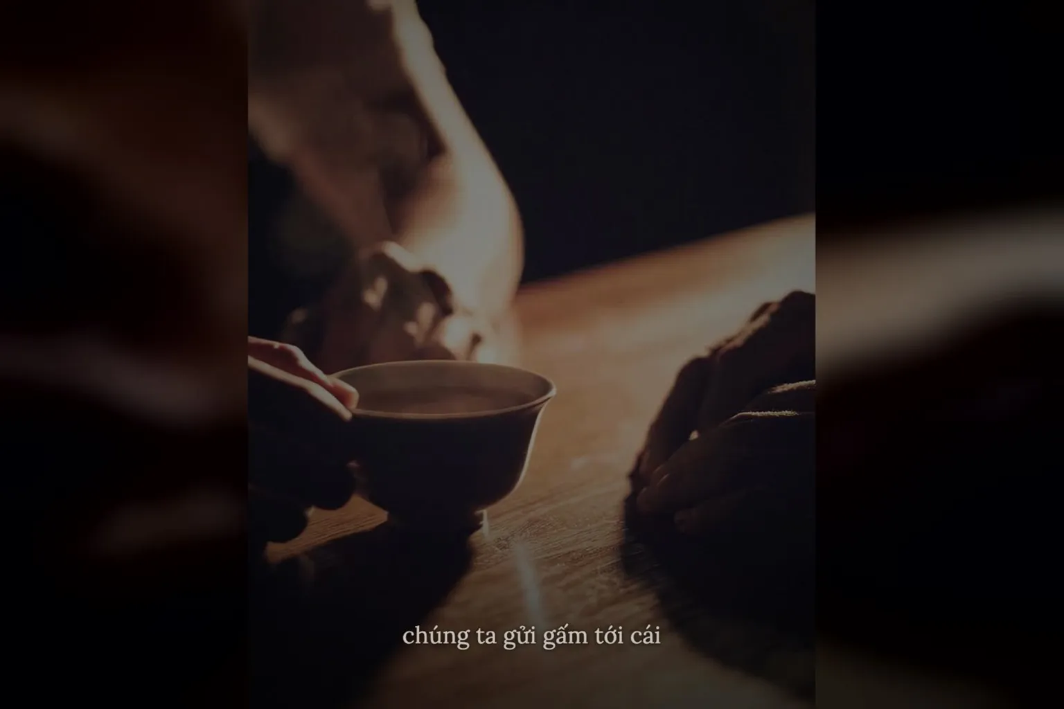 B-roll AI tạo theo câu gửi gắm khách hàng: đôi bàn tay đưa ly trà trên bàn gỗ tối