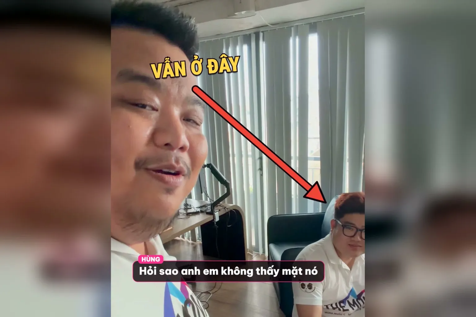 Hùng cầm điện thoại quay, mũi tên VẪN Ở ĐÂY chỉ vào Triết ngồi bàn phía sau